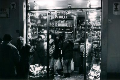 Extérieur-intérieur
Photo prise depuis la rue en début de nuit. Spotmatic SP 50mm 400asa f/1,4 1/30e de sec à main levée.
Un débit de boisson ---excellent--- dans une ruelle florentine. Les consommateurs boivent au comptoir devant les bouteilles ouvertes pour un verre, ou goûtent le vin dans la rue à proximité du marché.
